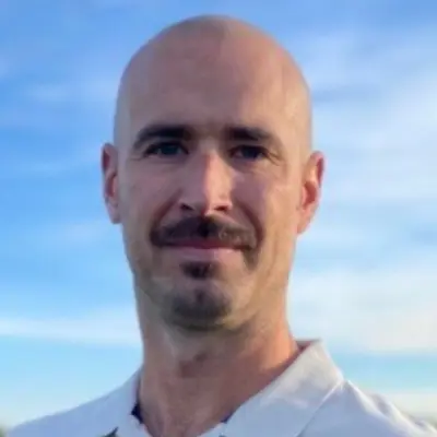 Portrait of Candidate Alan Wiese against a blue sky with a neutral expression and a light polo shirt.