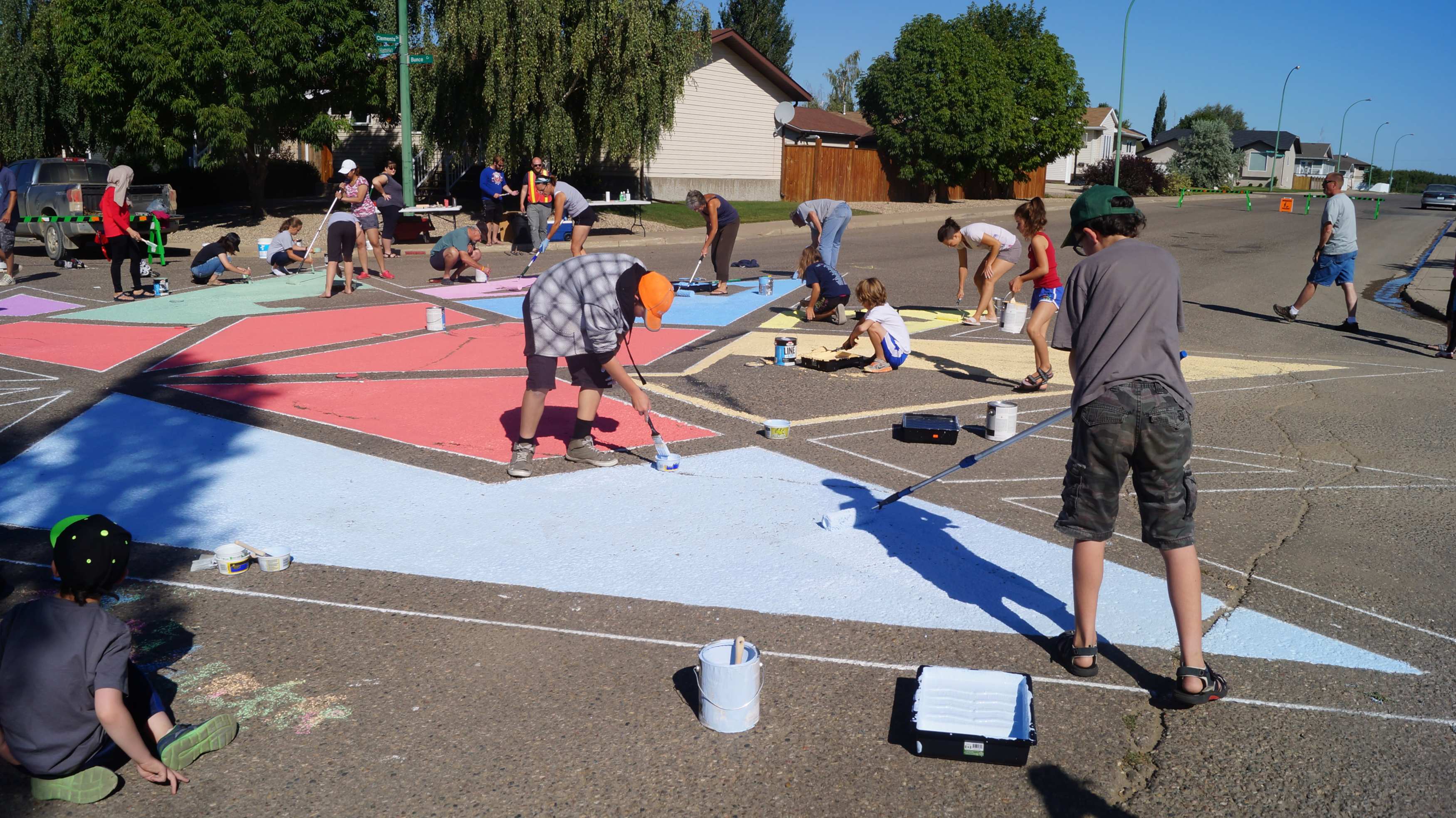 Community members painting a colorful mural on a street, engaging in teamwork and creativity.