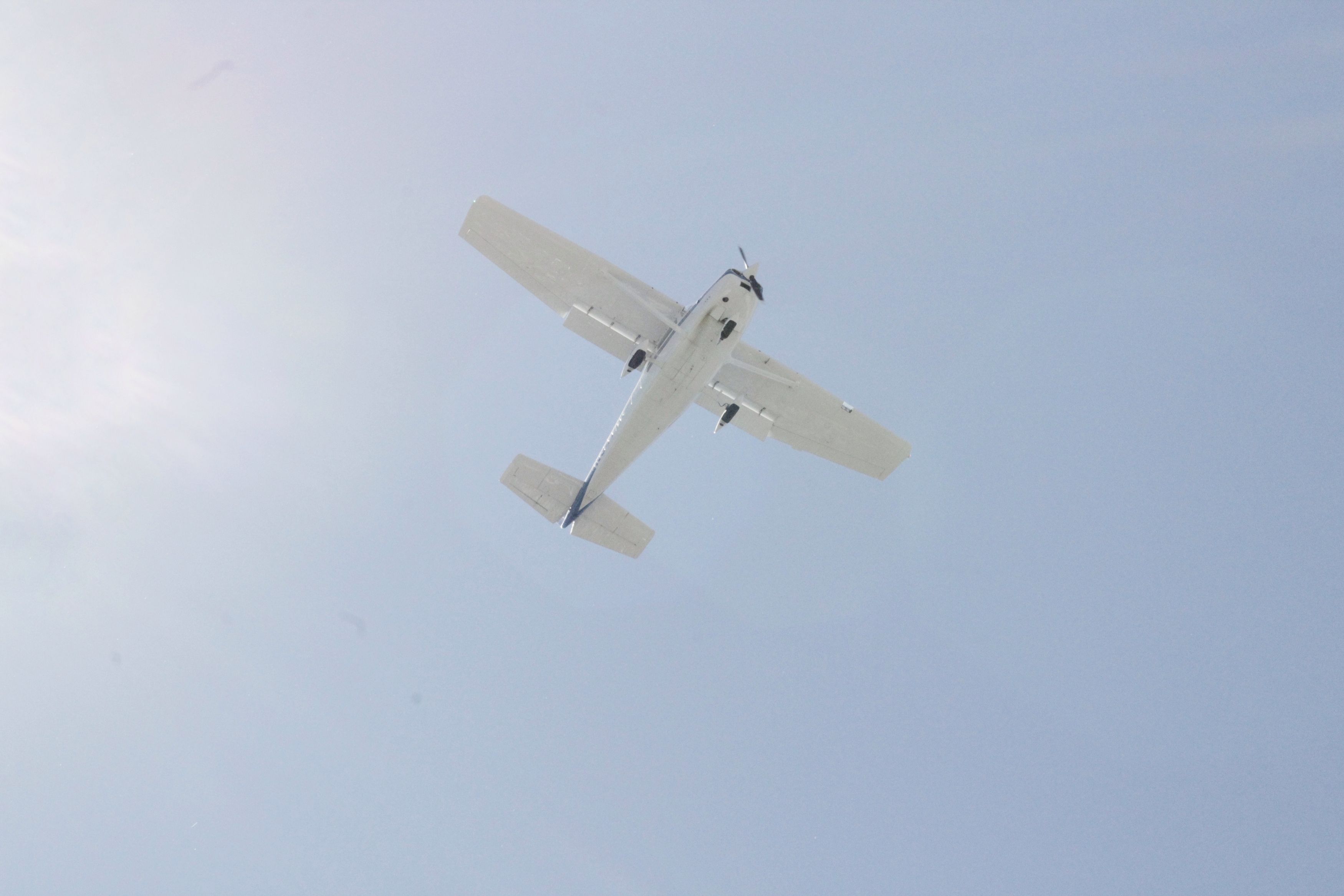 A single propeller airplane flying directly above in a blue sky filled with white clouds.