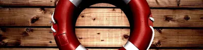 A red and white life preserver mounted against a wooden background.